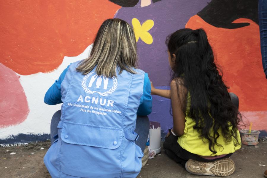 UNHCR staff painting with a child. 